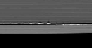 Moons in the rings create vertical waves due to gravitational forces.
